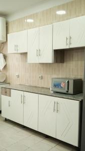 a kitchen with white cabinets and a microwave on a counter at Sheba Palace Apartment in Addis Ababa