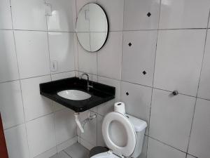 a bathroom with a sink and a toilet and a mirror at Casa jardim fonte nova in Goiânia