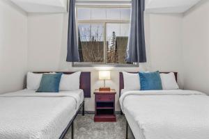 two beds in a room with a window at Mystic Springs #108 - Hot Tub and Pool, Pets managed by Little Sister Getaways in Canmore