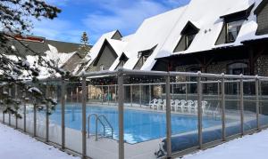 a swimming pool in front of a house in the snow at Mystic Springs #108 - Hot Tub and Pool, Pets managed by Little Sister Getaways in Canmore +32 photos