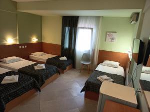 ein Hotelzimmer mit drei Betten und einem Fernseher in der Unterkunft SKG Assembly Β&Β Hotel in Thessaloniki