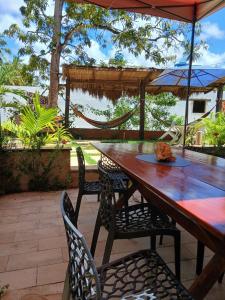 a wooden table with chairs and an umbrella on a patio at Lotus Antunes Beach in Antunes