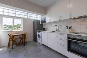 a kitchen with white cabinets and a sink and a dishwasher at Carcavelos Village III By Staycalm in Carcavelos
