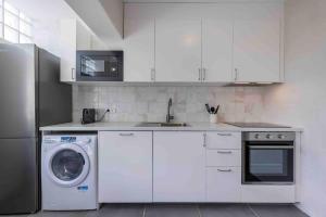 a white kitchen with a washing machine and a refrigerator at Carcavelos Village III By Staycalm in Carcavelos +11 photos