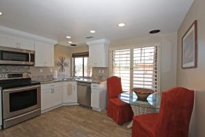 a kitchen with white cabinets and a table and red chairs at Balcony-Views-Country Club Living-VV667 in Palm Desert +28 photos