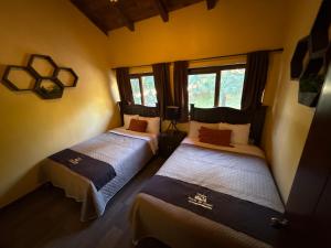 two beds in a room with yellow walls and windows at Hermosa cabaña con terraza para disfrutar Cabañas puerta del bosque Mazamitla in Mazamitla