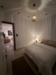 a bedroom with a large white bed and a mirror at Nestlya Apartment in Sukrah