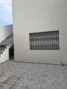 a white wall with a metal fence on it at Nestlya Apartment in Sukrah