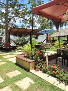 a patio with a bunch of flowers and an umbrella at Lotus Antunes Beach in Antunes