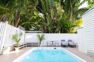 a swimming pool with chairs and a white fence at The Margaret Suite in Key West
