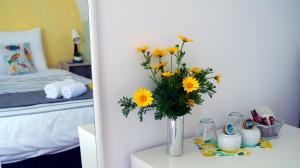 a vase of yellow flowers on a table in a bedroom at Kalimera Aegina in Agia Marina Aegina