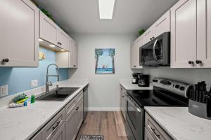 a kitchen with white cabinets and black appliances at Bikini Bottom Destin Harbor Private Gated Beach in Destin