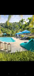 a large swimming pool with blue umbrellas and tables at Navela in Ko Lanta