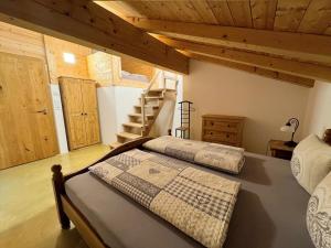 two beds in a bedroom with wooden ceilings and stairs at Ferienwohnungen Kieferbachtal in Kiefersfelden