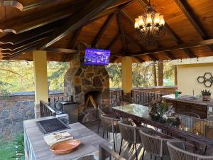 an outdoor patio with a stone fireplace and a television at Hermosa cabaña con terraza para disfrutar Cabañas puerta del bosque Mazamitla in Mazamitla