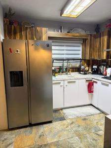 a kitchen with a stainless steel refrigerator and white cabinets at Comfort House in Manuel F. Martínez