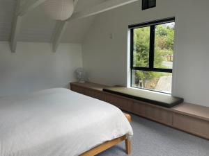 a white bedroom with a bed and a window at Matakana Retreat - Luxury Off Grid Lodge in Nature in Matakana