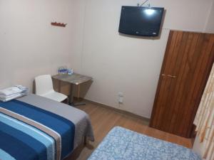 a bedroom with a bed and a desk and a television at La Posada in Cajamarca