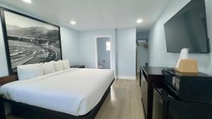 a bedroom with a large white bed and a flat screen tv at Pelican Inn in Monterey