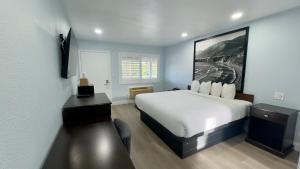 a bedroom with a white bed and a desk and a window at Pelican Inn in Monterey