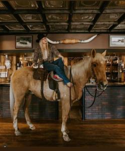 Eine Frau sitzt auf einem Pferd in einem Geschäft in der Unterkunft Twin Cities Hotel in Turner Valley