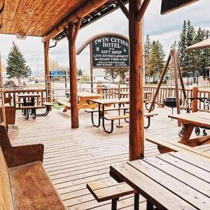 eine Holzterrasse mit Picknicktischen und einem Schild in der Unterkunft Twin Cities Hotel in Turner Valley