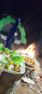 two plates of food and a bottle of wine next to a fire at Sunshine Holiday Inn Ella in Ella