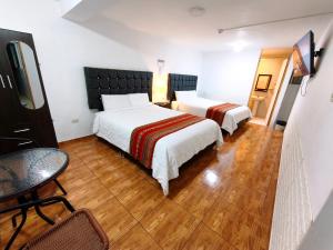 a hotel room with two beds and a table and a tv at Hostal Cusco de mis Sueños in Cusco