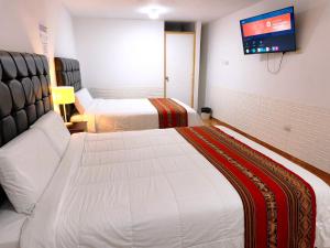 a hotel room with two beds and a flat screen tv at Hostal Cusco de mis Sueños in Cusco
