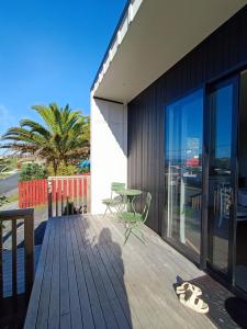 eine Holzterrasse mit Tisch und Stühlen an einem Haus in der Unterkunft The Tiny Abode in Snells Beach
