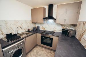 a kitchen with a sink and a washing machine at Queensferry Collection - Residence 2 in Derby