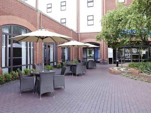 an outdoor patio with tables and chairs and umbrellas at Novotel Ipswich Centre in Ipswich