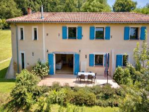 a house with blue shutters and a table in front of it at 7-Bedroom Tarn Villa with Spa in Damiatte