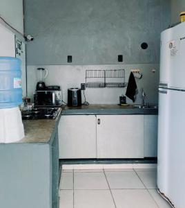 a kitchen with white cabinets and a refrigerator at Surf & Arte Hostel in Cabo Frio