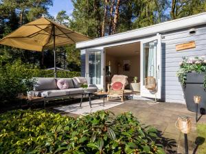 a backyard patio with a couch and an umbrella at Boschalet Stijn in Hattemerbroek