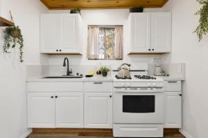 a white kitchen with a stove and a sink at Shiloh Woods Cabin Walk to Lake & Village Fireplace Cozy Retreat in Big Bear Lake +17 photos