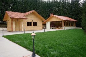 a log cabin with a grass yard and a building at Pensiunea Floarea de Colt in Nucşoara