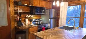 a kitchen with a counter with a sink and a refrigerator at Timber Wood, Log Cabin, Private Hot Tub, WiFi, Fireplace in Sevierville