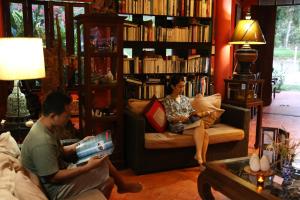 a man and a woman sitting on a couch in a library at NATUR - Krabi Campsite Glamping & Camping in Krabi