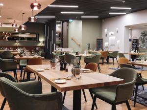a restaurant with tables and chairs in a room at Mercure Luxembourg Kikuoka Golf & Spa in Canach