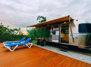 an rv parked on a deck with a chair and a patio at Airstream Stay Private Jacuzzi & Volcano View in Monterrey