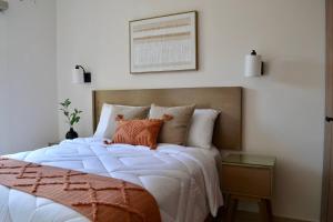 a bedroom with a large bed with an orange pillow at Encanto Department We Bill in Alcocer