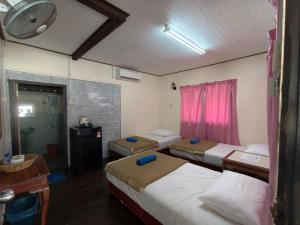 a room with three beds and a desk and a window at Nazri's Place 2 in Tioman Island