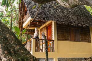 a woman standing on a balcony of a house at L'Astrolabe - Private Beach in Baras