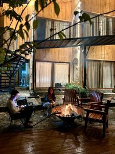 two people sitting around a fire in front of a building at Phỏng Lài Mountain Homestay - Ta Xua Peak View in Bắc Yên