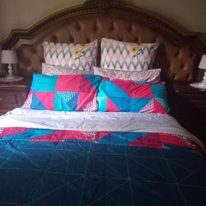 a bed with colorful blankets and pillows on it at Town Charm Guesthouse in Germiston
