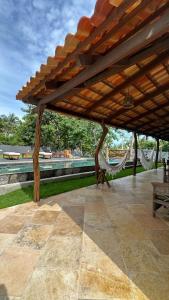 a pavilion with a hammock and a table and benches at villa coqueiro praia do prea in Cruz