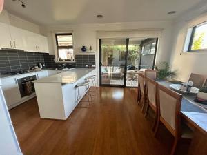 a kitchen with white cabinets and a wooden floor at Modern Gem Steps from Everything You Need in Croydon North