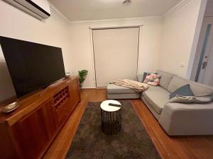 a living room with a couch and a flat screen tv at Modern Gem Steps from Everything You Need in Croydon North