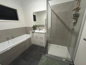 a bathroom with a shower and a tub and a sink at Modern Gem Steps from Everything You Need in Croydon North +8 photos